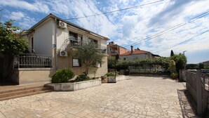 A residential building with a paved courtyard, a balcony, and a small garden area. - Rooms and Studio Salvi (Rovinj)