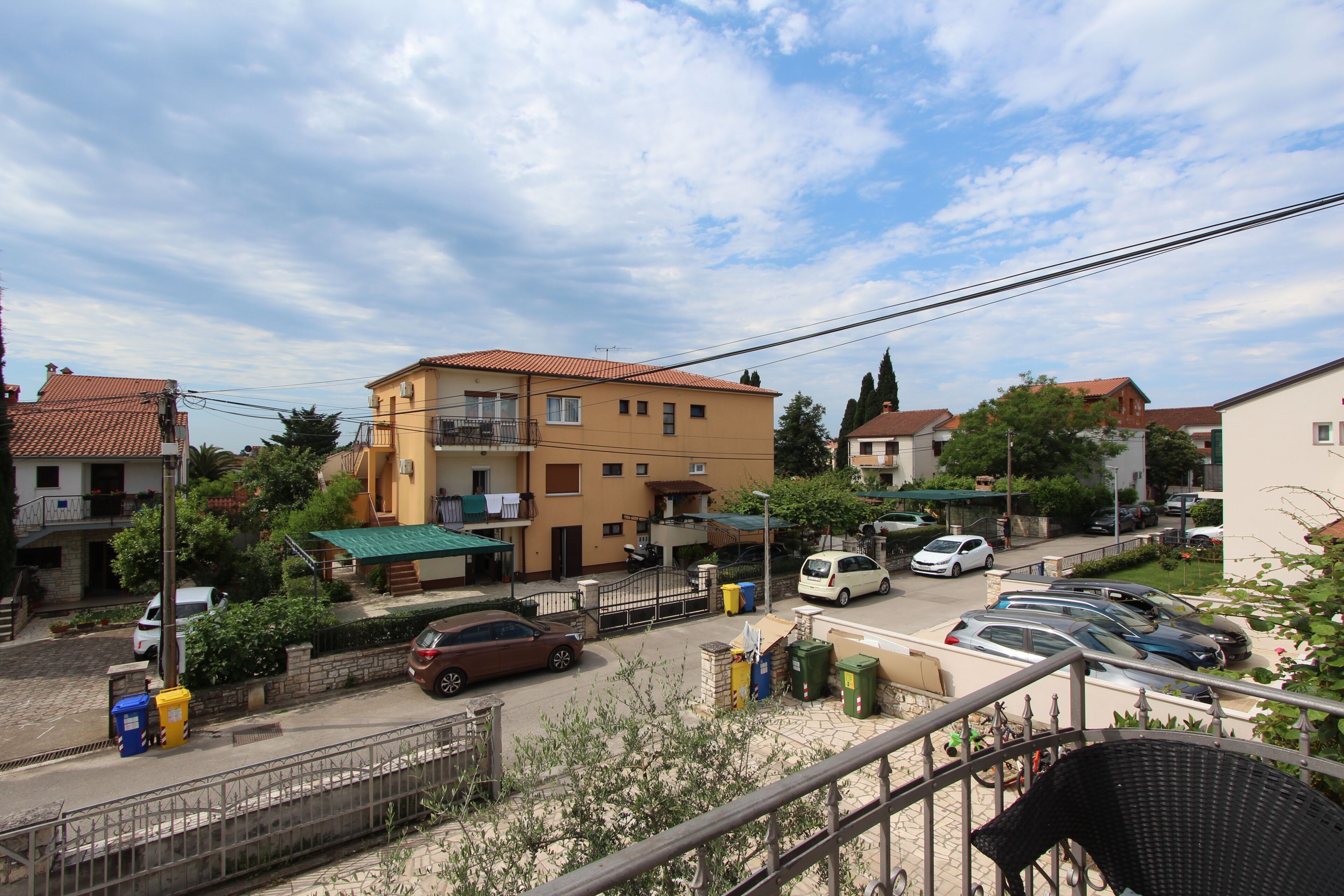 Una calle residencial con casas, coches aparcados y cielo despejado.