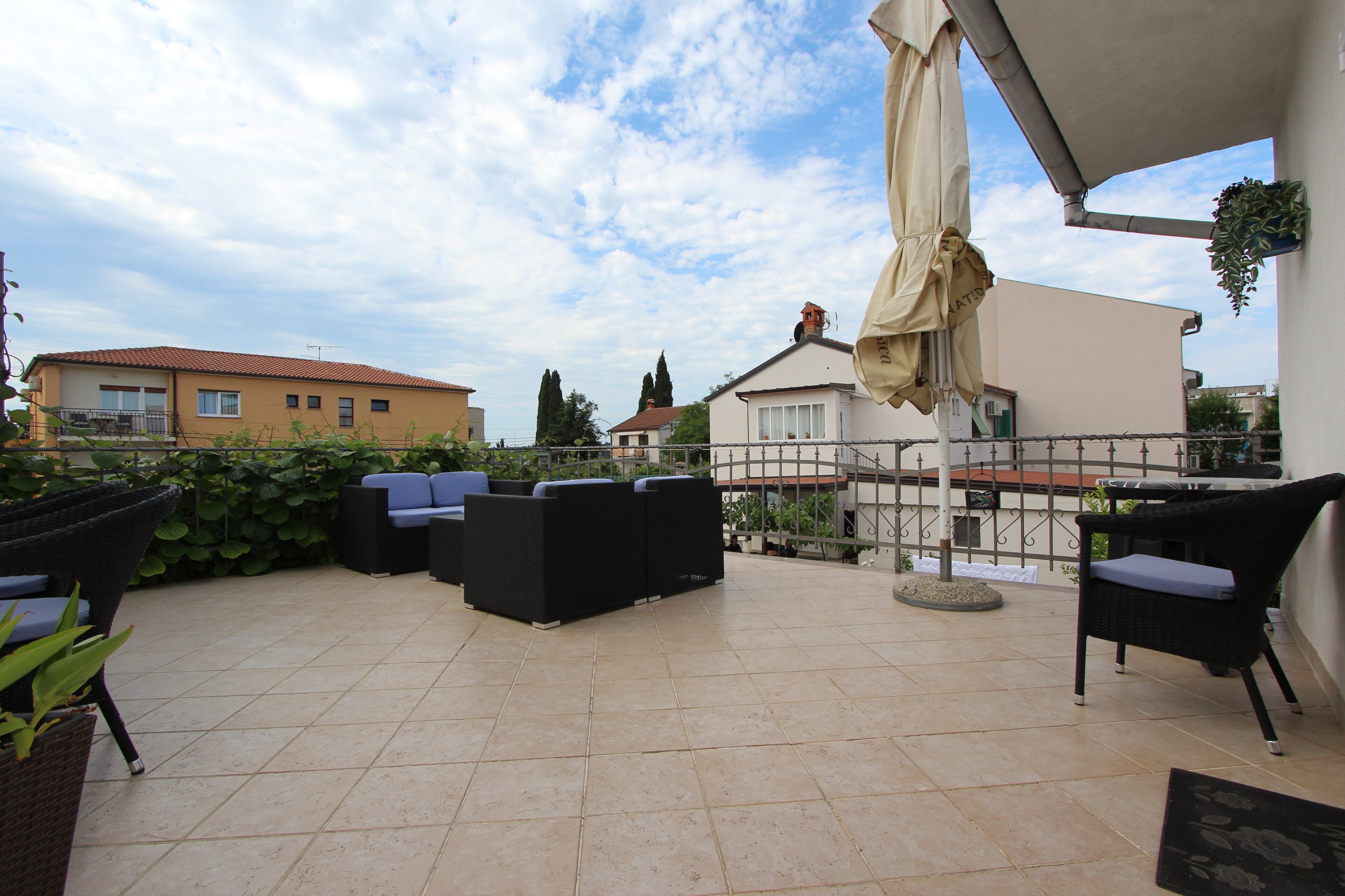 Um terraço no telhado com mobiliário de exterior, uma pérgula e vista para edifícios circundantes.
