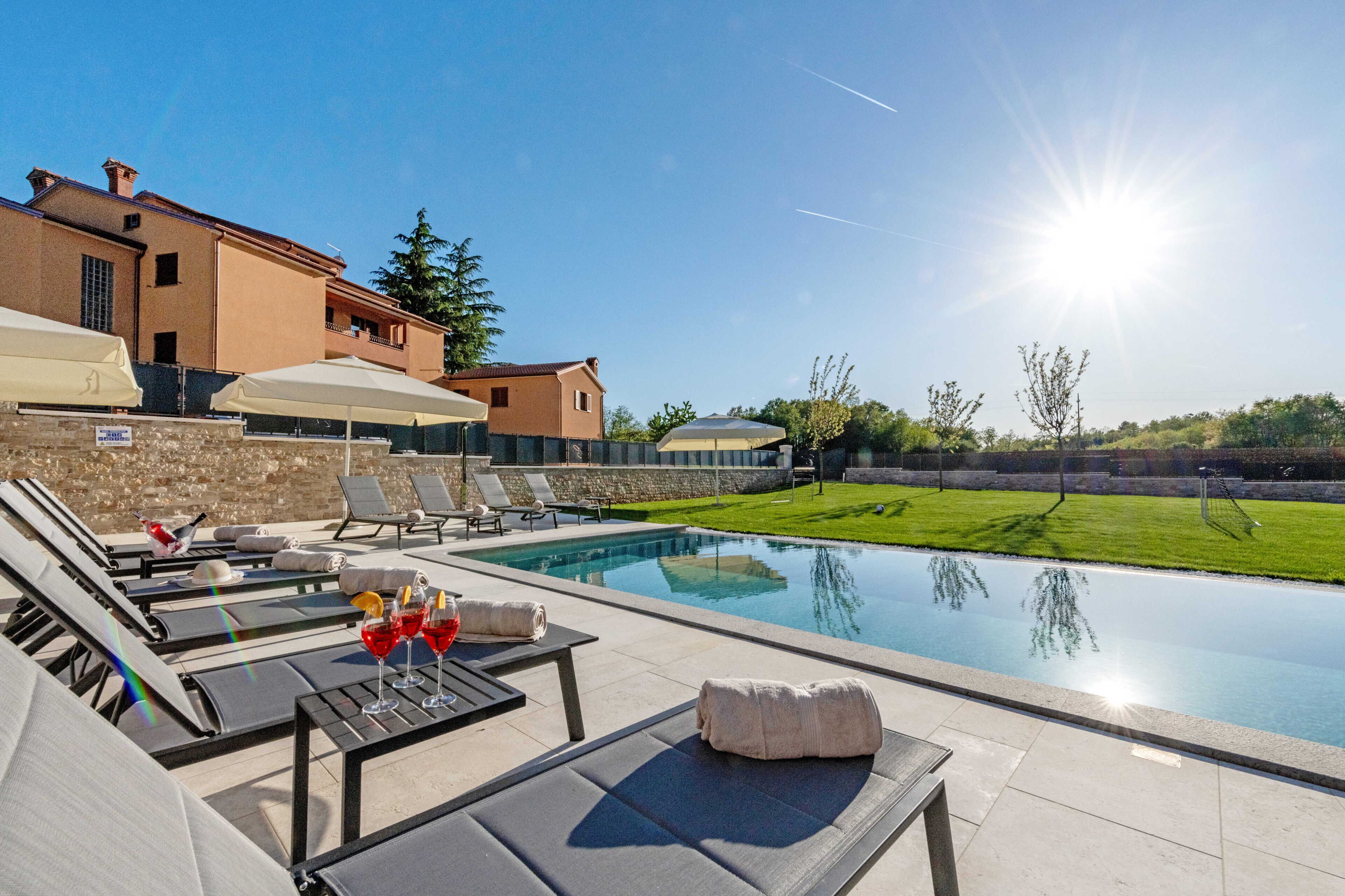 A poolside area with lounge chairs, umbrellas, and a clear view of the pool.