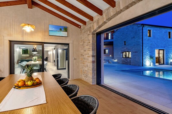 A dining area with a wooden table, chairs, and a fruit bowl. - Villa Ciburi in Pazin, Istria: 320 m² living space, room for 16 people (Lovrin)