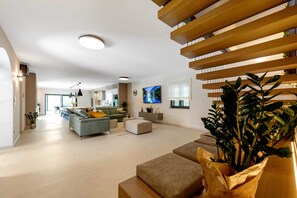A modern living room with a sofa, ottoman, and a large plant. - Villa Ciburi in Pazin, Istria: 320 m² living space, room for 16 people (Lovrin)