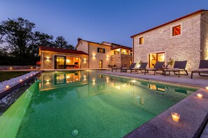 A poolside area with a stone building, outdoor seating, and a clear pool. - Villa Ciburi in Pazin, Istria: 320 m² living space, room for 16 people (Lovrin)