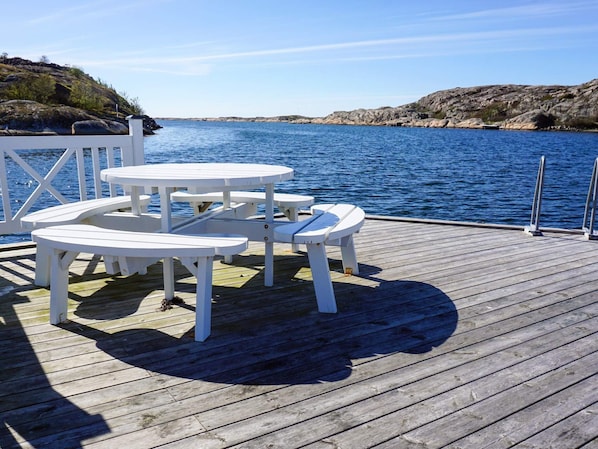 A wooden deck with white picnic tables overlooking a body of water.
