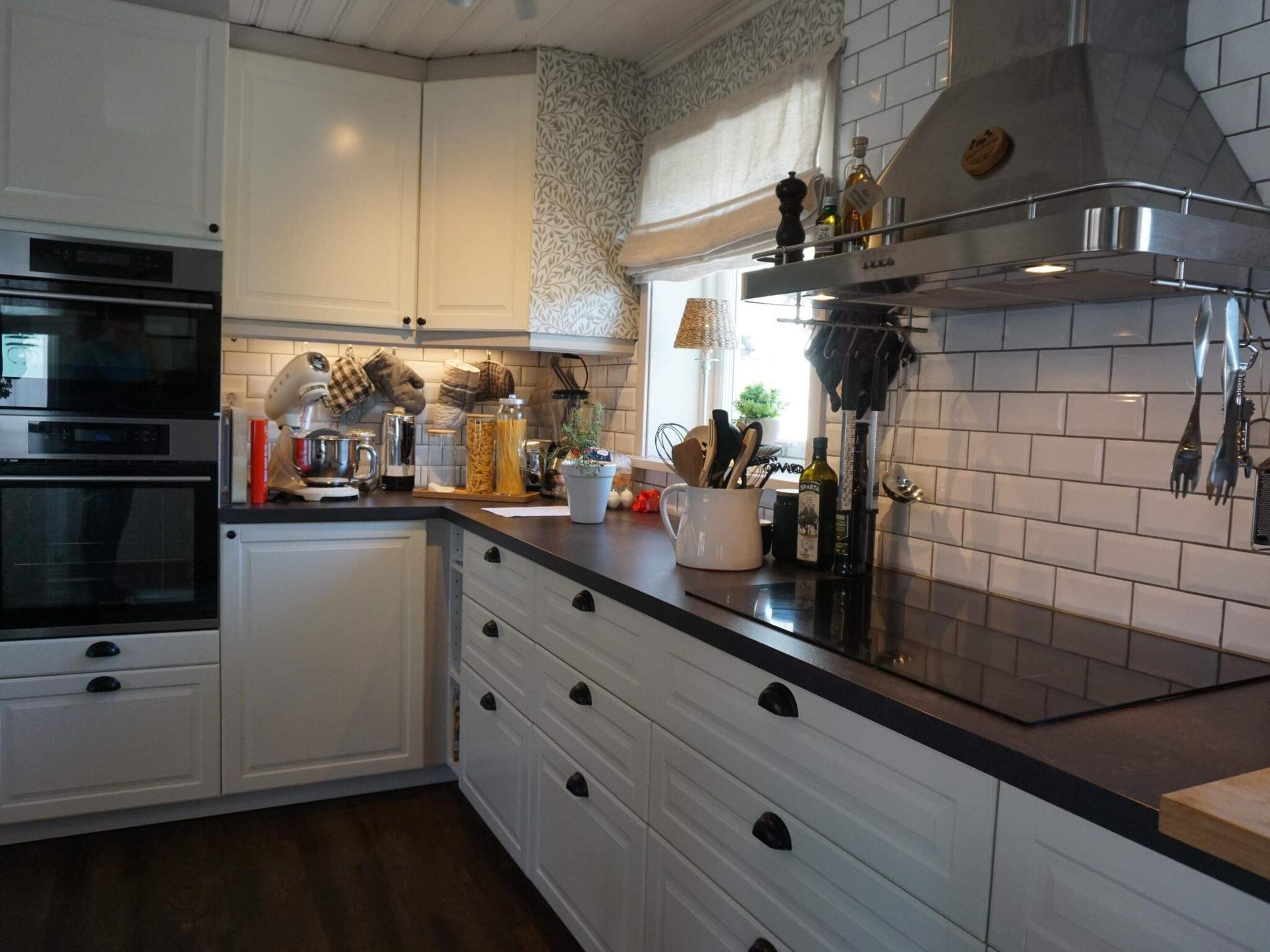 A modern kitchen with white cabinetry, a black countertop, and stainless steel appliances.