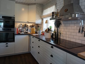 A modern kitchen with white cabinetry, a black countertop, and stainless steel appliances. - 4 Star Holiday Home in Kungshamn (Kungshamn)