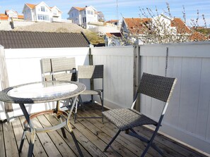 A deck with a glass-top table and wicker chairs, surrounded by a white fence. - 4 Star Holiday Home in Kungshamn (Kungshamn)