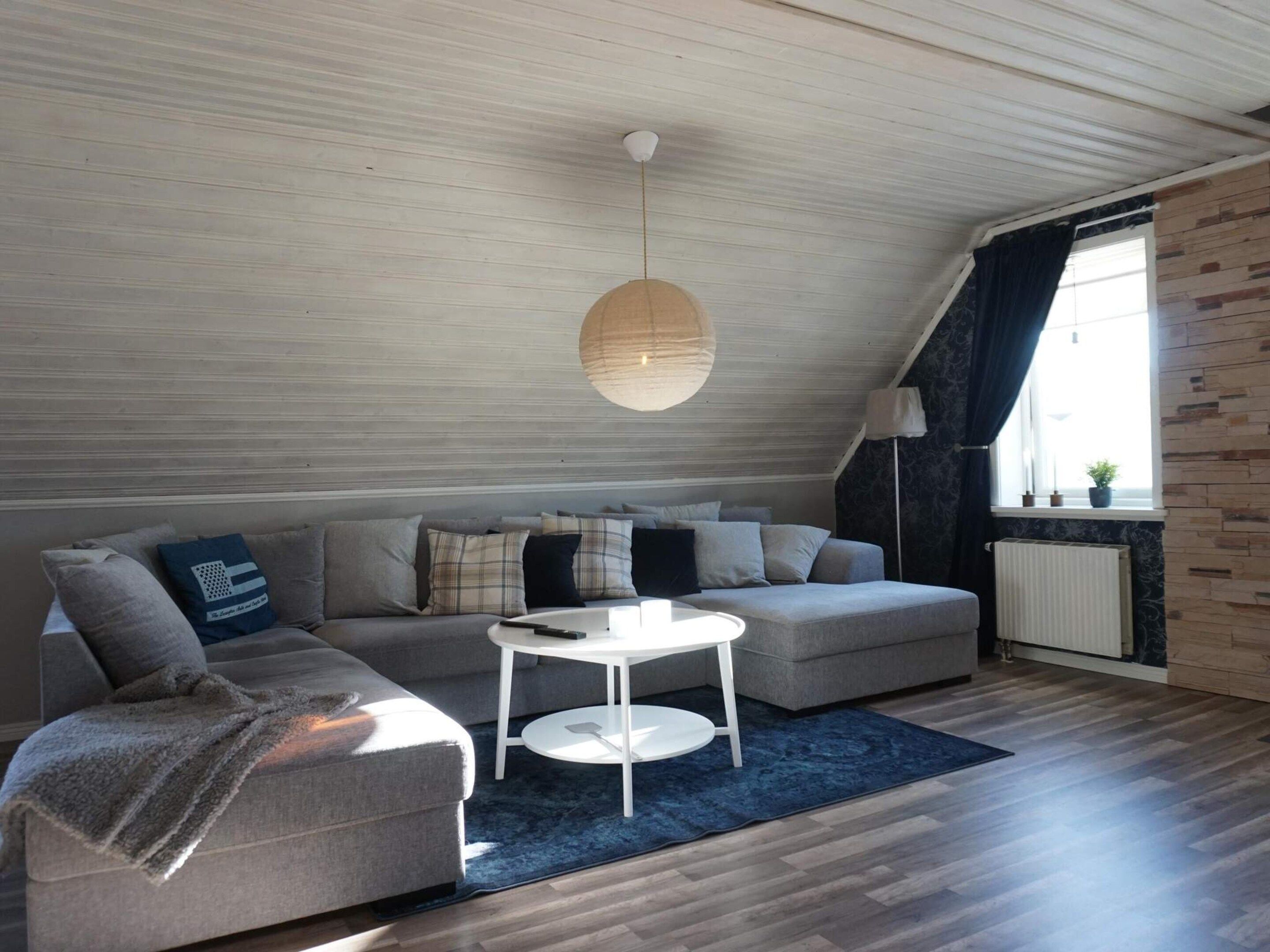 A modern living room with a sectional sofa, a round coffee table, and a hanging light fixture.