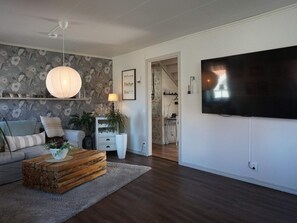 A living room with a sofa, coffee table, TV, and a staircase leading to another room.