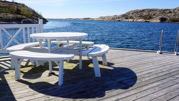 A wooden deck with white picnic tables overlooking a body of water.