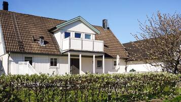 A two-story house with a sloped roof, a front porch, and a small balcony.