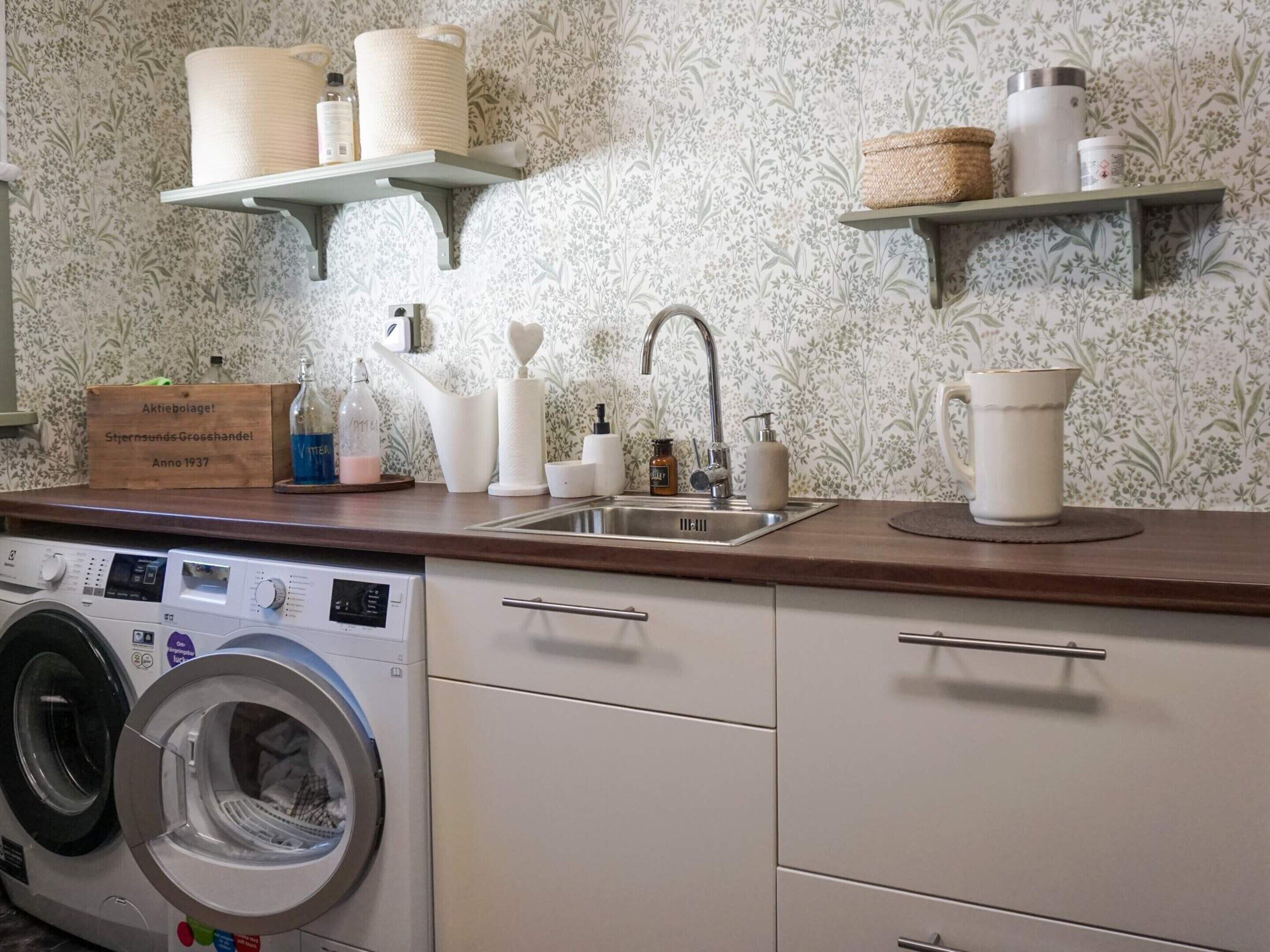 Un espace buanderie comprenant un lave-linge, un évier et des étagères avec des paniers et des articles de toilette.