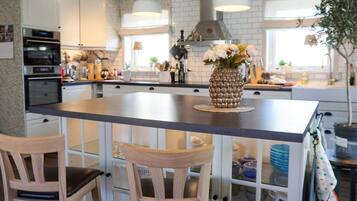 A kitchen with white cabinets, a central island with chairs, and pendant lighting.