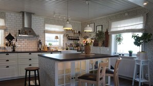 A kitchen with a central island, white cabinetry, and pendant lighting. - 4 Star Holiday Home in Kungshamn (Kungshamn)