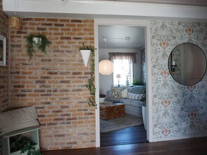 A room with a brick wall, a round mirror, a patterned wallpaper, and a wooden floor. - 4 Star Holiday Home in Kungshamn (Kungshamn)