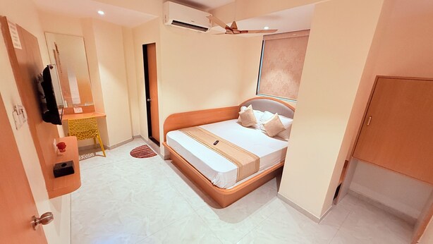 A bedroom with a bed, a ceiling fan, an air conditioning unit, a small desk, and a wardrobe. - Radhe Residency MIDC Taloja  (Panvel)