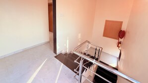 A staircase with metal railings, a wooden door frame, and a red fire hose on the wall. - Radhe Residency MIDC Taloja  (Panvel)