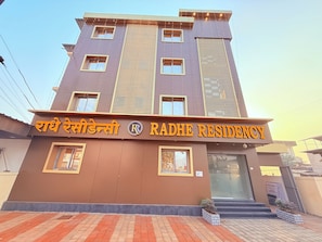 A multi-story building with a sign reading 'RADHE RESIDENCY' and a logo. - Radhe Residency MIDC Taloja  (Panvel)
