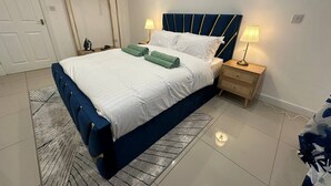 A hotel room with a bed, two bedside tables, a hanging coat rack, and a door.