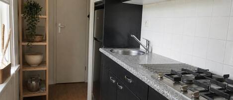 A kitchen with black cabinets, a granite countertop, a stainless steel sink, and a microwave.