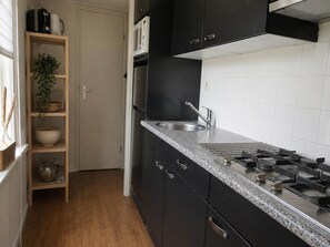 Una cocina con gabinetes negros, encimera de granito, pileta de acero inoxidable y microondas.