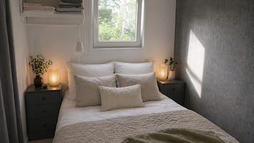 A bedroom with a bed, bedside tables, a window, and a shelf with towels.
