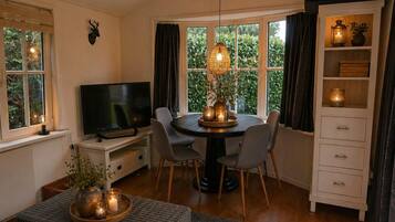 A cozy living room with a TV, dining table, chairs, and a fireplace.