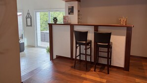 Ein Zimmer mit Holzboden, einer weißen Wand, einem Fenster und zwei Stühlen.