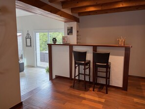 Ein Zimmer mit Holzboden, einer weißen Wand, einem Fenster und zwei Stühlen.