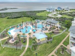 A resort with a large pool area, multiple buildings, and a view of the ocean. - Bay Dreaming-Book 5+ nights & get 15% discount-Lazy River-3BD/3BA Sleeps 10 (Galveston)