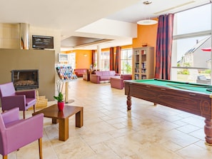 A billiards table, a fireplace, and a pool table in a room with orange walls and large windows. - Azay-le-rideau Castle Retreat (Azay-le-Rideau)