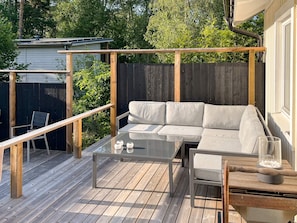 Eine Terrasse mit Tisch, einer Couch und einem Sessel.
