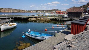 A calm harbor with boats docked, a wooden pier, and a small building with a red roof. - 4 Star Holiday Home in Tanumshede (Tanum)