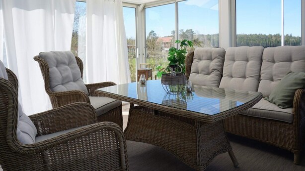 A sunroom with wicker furniture, large windows, and a view of the outdoors. - 4 Star Holiday Home in Tanumshede (Tanum)