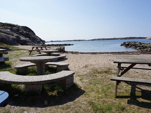 A beach with picnic tables and a rocky shoreline.