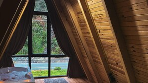 A cozy room with a bed, a wooden floor, a window with curtains, and a hot tub. - Roadside bungalov  (RİZE)
