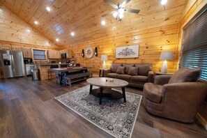 A wooden cabin interior with a kitchen, dining area, and living room. - Enchanted Pines: Find Your Magic in the Mountains (Pigeon Forge)