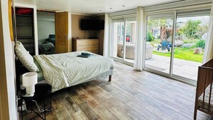 Ein Schlafzimmer mit Bett, Fernseher, einer Schiebetür zu einem Garten und einem Einbauschrank.