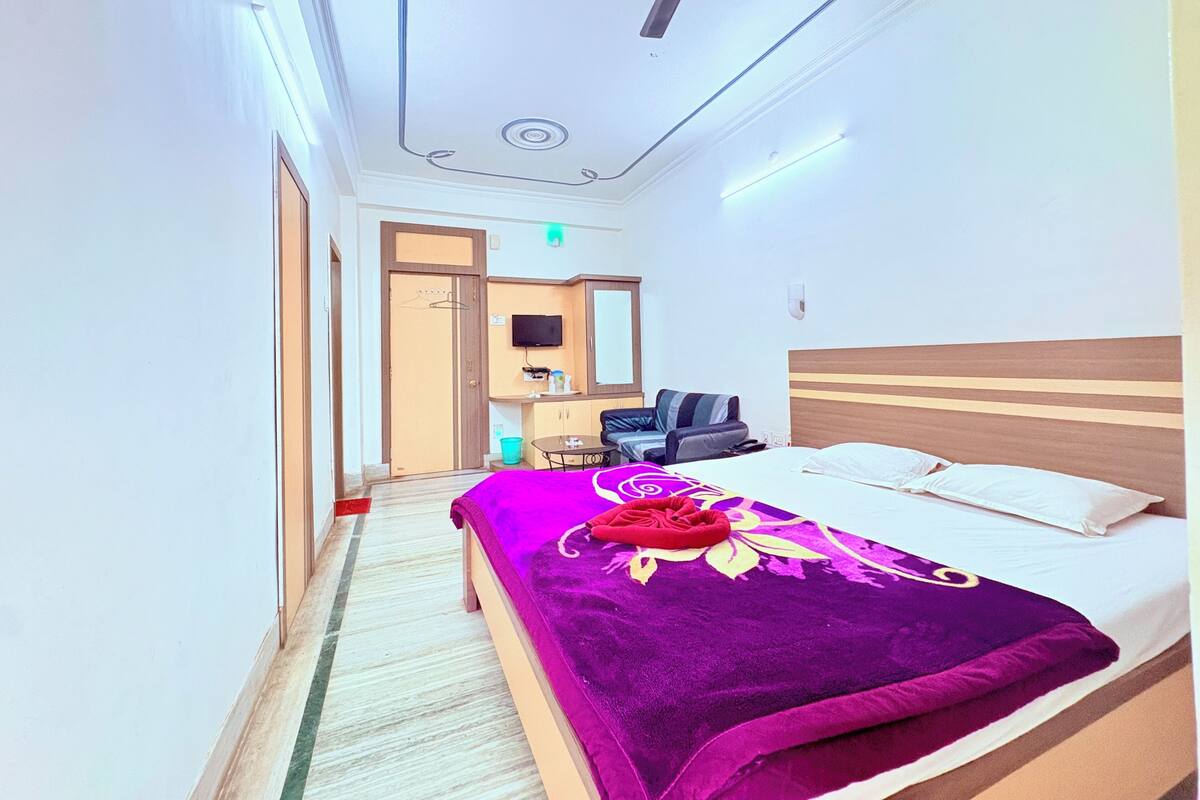 A hotel room with a bed, a desk, a chair, a television, and a ceiling fan.