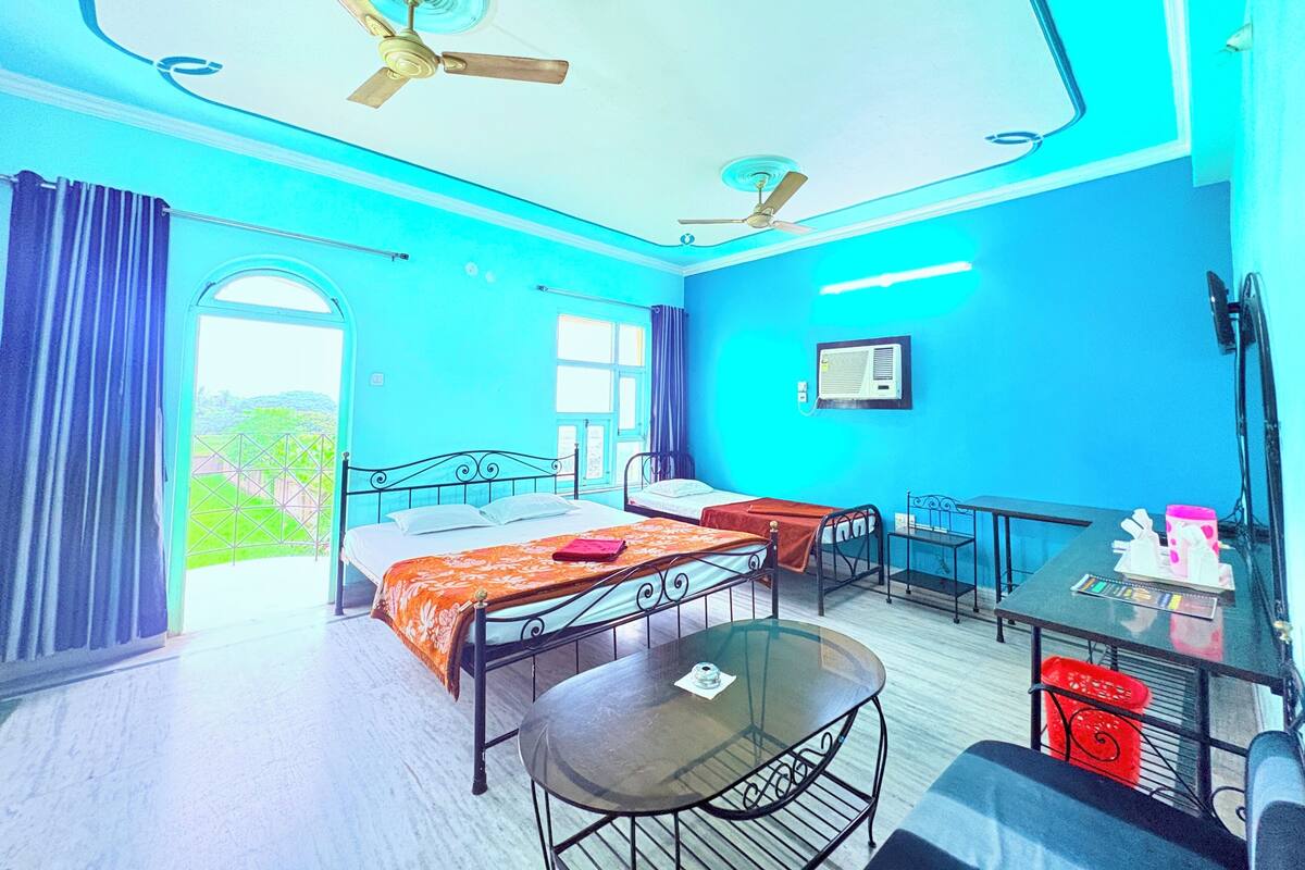 A hotel room with a bed, a table, a chair, a ceiling fan, and a window.