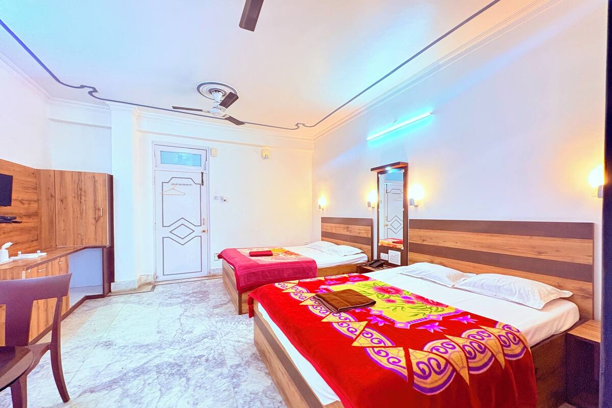 A hotel room with a bed, bedside table, chair, desk, and a mirror.