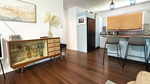 Una cocina moderna con refrigerador, taburetes de bar y comedor con piso de madera.