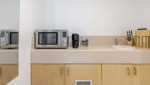 Una cocina equipada con microondas, cafetera, lavabo y bloque de cuchillos.