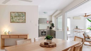 Uma cozinha moderna com armários brancos, micro-ondas e um espaço de refeições com mesa e cadeiras de madeira.