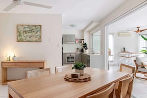 Uma cozinha moderna com armários brancos, micro-ondas e um espaço de refeições com mesa e cadeiras de madeira.