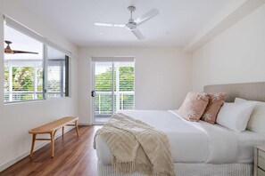 A bedroom with a bed, a bench, a ceiling fan, and a view through a window. - A Calm City Base Cairns CBD (Cairns)