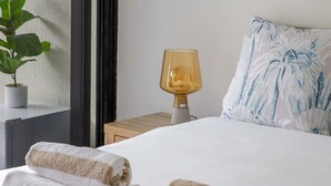 Camera d'albergo con un letto, due asciugamani, un comodino con una lampada, una pianta in vaso e una finestra con vista.