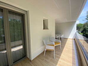 Ein Balkon mit Schiebetür, einem kleinen Tisch und zwei weißen Stühlen.