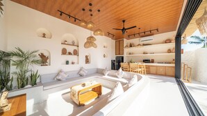 Een moderne woonruimte met een houten plafond, inbouwkasten, een keukenhoek en een zithoek met een bijzettafeltje.