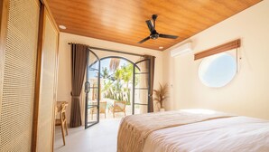 Een slaapkamer met een bed, een plafondventilator, een raam en uitzicht op de omgeving.
